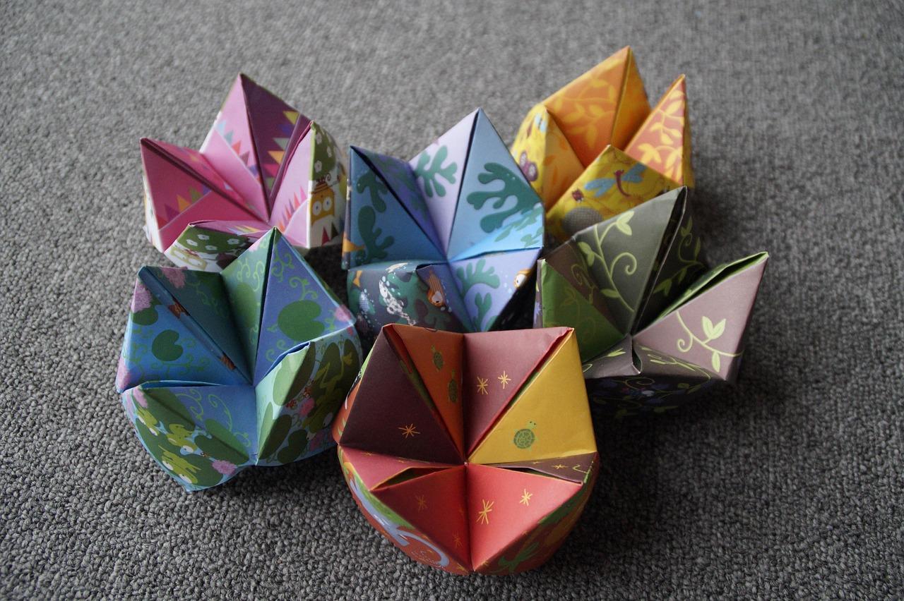 Buntes, gefaltetes Papier in Origami-Technik auf grauem Hintergrund